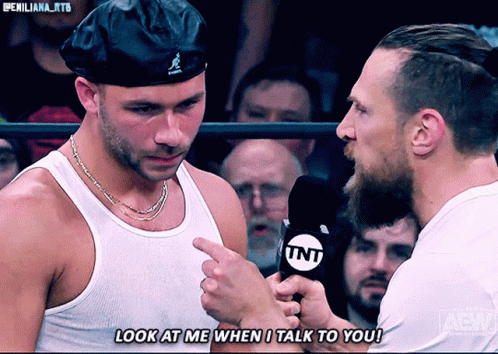 Man Talking Into TNT Microphone While Another Man Looks On