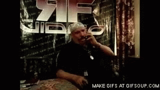 Man Talking on Cell Phone at Table with 21 Video Sign