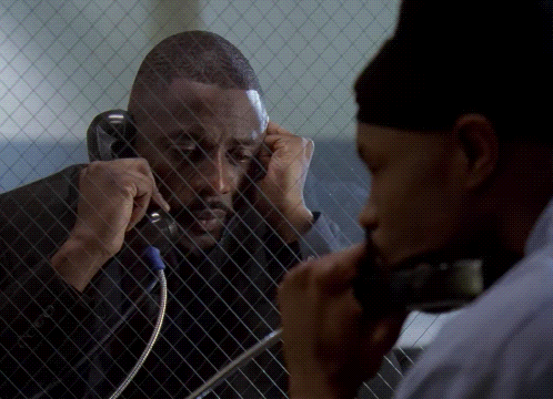 Man Talking on Cell Phone Behind Fence