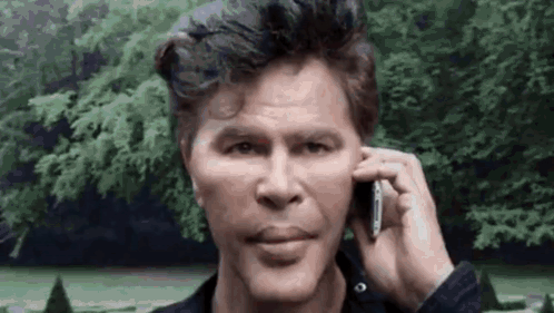 Man Talking On Cell Phone In Front Of Trees GIF