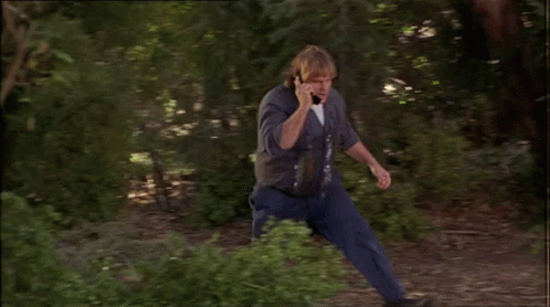 Man Talking On Cell Phone Leaning Against Tree Branch GIF