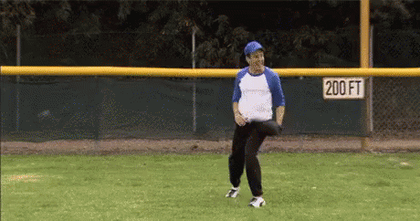 Man Throwing Baseball on Field With 200ft Sign