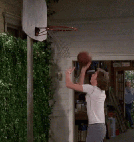 Man Throwing Basketball Through Hoop in Front of Garage Door