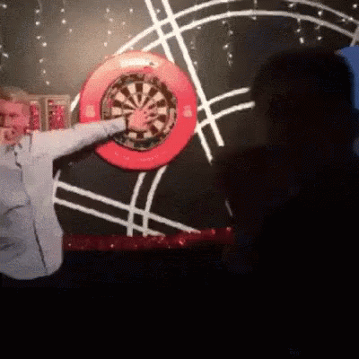 Man Throwing Dart At Red Rim Dart Board GIF