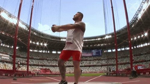 Man Throwing Shot Put in Stadium with Name Lock