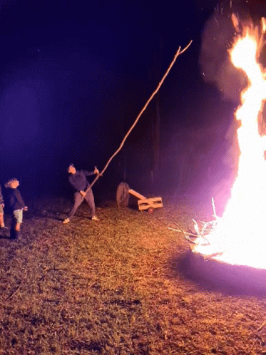 Man Throws Stick by Large Fire