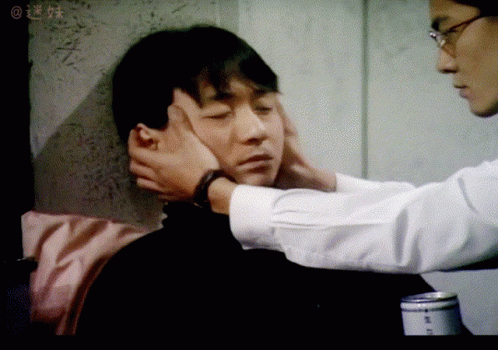 Man Touching Another Man's Face in Blurry Photo With Chinese Writing