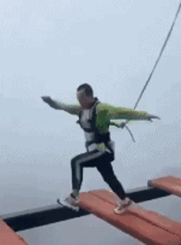 Man Walking Across Bridge With Arms Outstretched