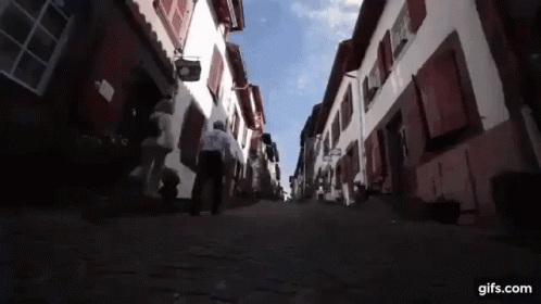 Man Walking Cobblestone Street With Gifs.com Sign GIF