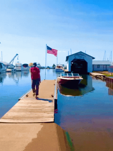 Man Walking Down Dock Past Boat Shed Saying Yacht & Yacht