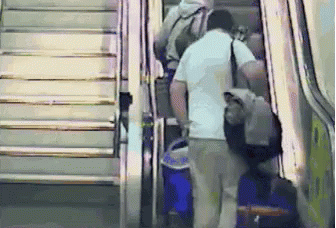 Man Walking Down Escalator With Blue Bag