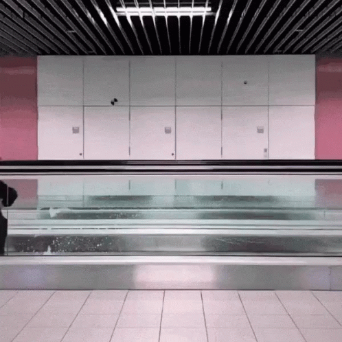 Man Walking Down Escalator With Blue Bag