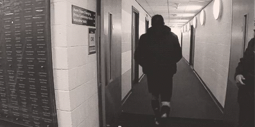 Man Walking Down Hallway With Intensive Suite Sign GIF
