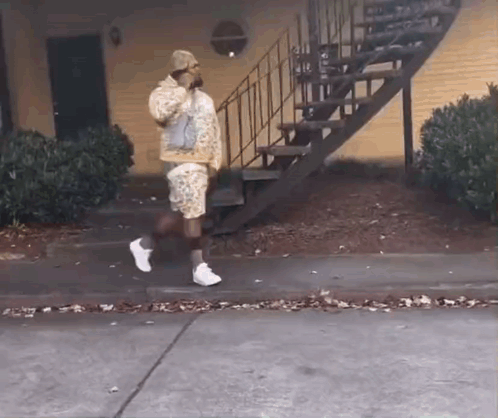 Man Walking Down Sidewalk Next to Stairs