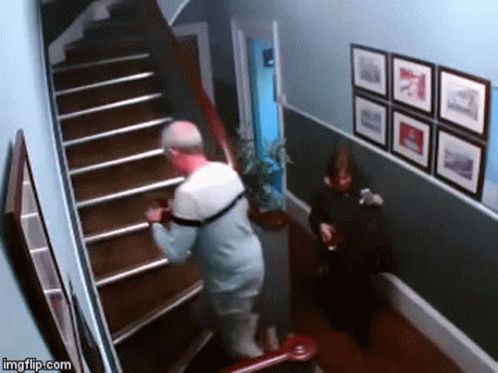 Man Walking Down Stairs While Woman Sits on Chair