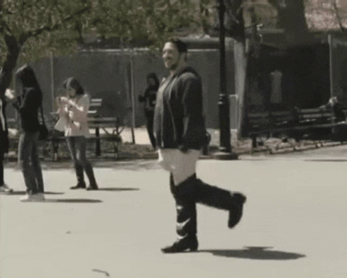 Man Walking in Park Looking at Phone
