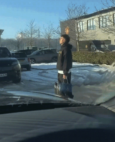 Man Walking in Parking Lot With Manchester United Logo