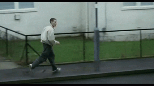 Man Walking On Sidewalk Next To Building GIF