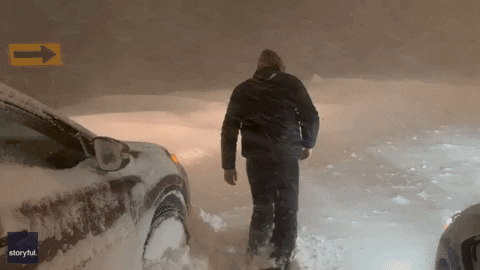 Man Walking On Snowy Road Amid Bomb Cyclone GIF