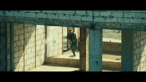 Man Walking Through Brick Building GIF