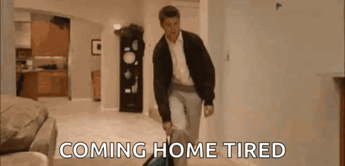 Man Walking Through Living Room With Suitcase Coming Home Tired