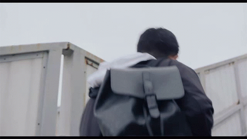Man Walking With Backpack and Towel on Head