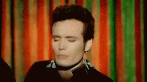 Man Wearing Choker Eyes Closed Before Colorful Curtain GIF