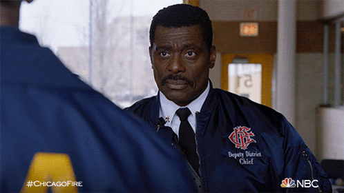 Man Wearing Deputy District Chief Jacket Talking to Another Man