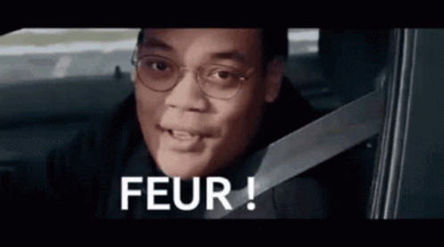 Man Wearing Glasses and Seat Belt in Car Saying Peur