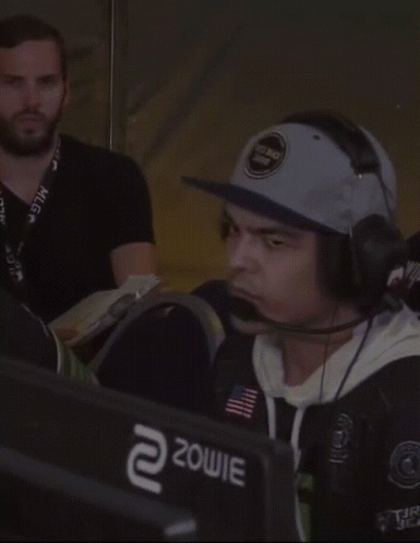 Man Wearing Hat and Headphones in Front of Zowie Monitor