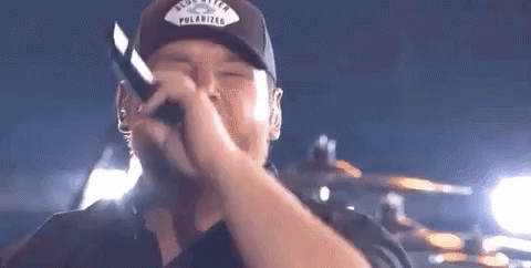 Man Wearing Hat Singing Into Microphone