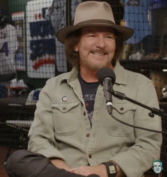Man Wearing Hat Sitting at Microphone