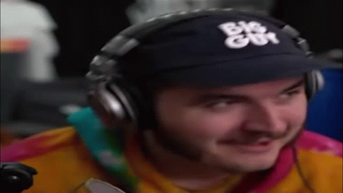 Man Wearing Headphones and Baseball Cap Smiling Playing Video Game