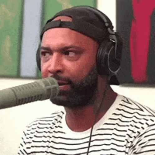 Man Wearing Headphones and Hat Talking Into Microphone
