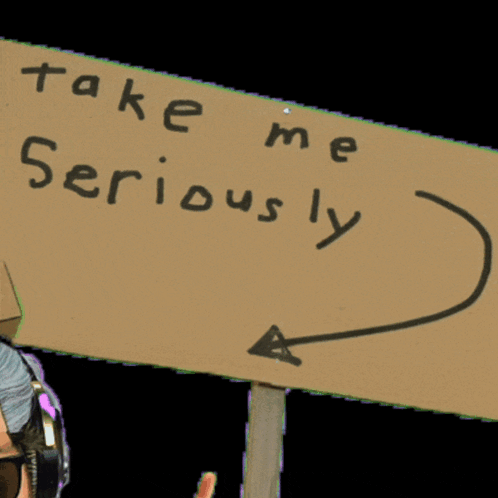 Man Wearing Headphones Holding Take Me Seriously Sign