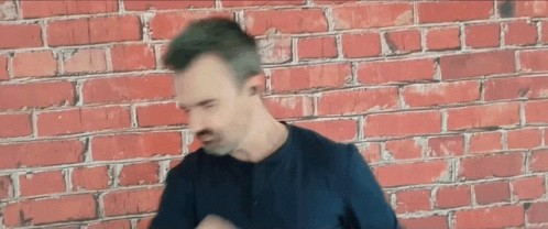 Man Wearing Headphones in Front of Brick Wall