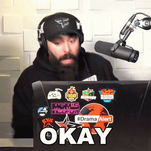 Man Wearing Headphones Sits in Front of Laptop Saying Okay
