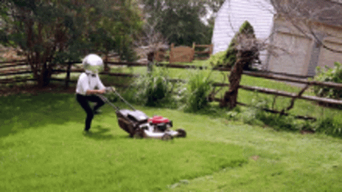 Man Wearing Helmet Mowing Lawn
