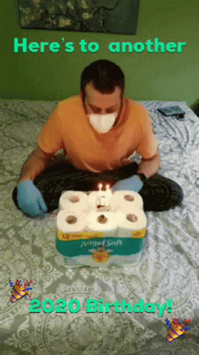 Man Wearing Mask Sitting on Bed with Toilet Paper Cake