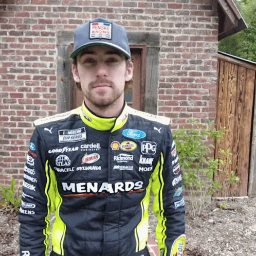 Man Wearing Menards Racing Suit At Brick Building GIF