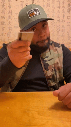 Man Wearing RVCA Hat Holding Card GIF