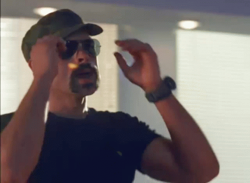 Man Wearing Sunglasses and Hat Smoking Cigar