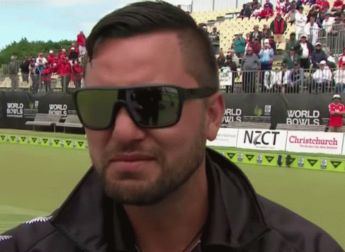 Man Wearing Sunglasses in Front of World Bowls Sign