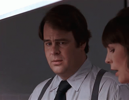 Man Wearing Suspenders and Tie Talks to Another Man