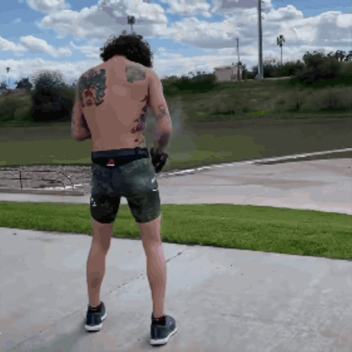 Man with Back Tattoo Standing on Sidewalk
