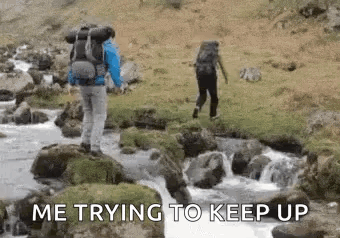 Man With Backpack Crossing River While Another Stands On Rock GIF