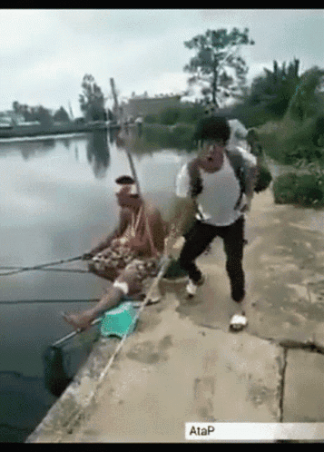 Man With Backpack Fishing in Lake, Another on Shore