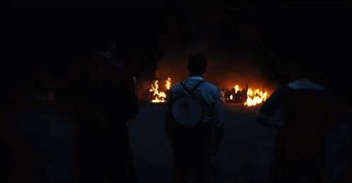 Man With Backpack In Front Of Fire GIF