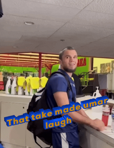 Man With Backpack In Front Of Green Sign Saying Aka GIF