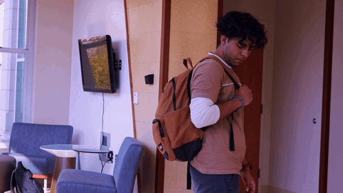 Man With Backpack Standing In Room With Flat Screen TV GIF